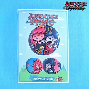 May include: A light blue card featuring Adventure Time character badges. The card has a light blue background with a white border. The badges feature cartoon characters with pink and blue hair. The Adventure Time logo is at the top.
