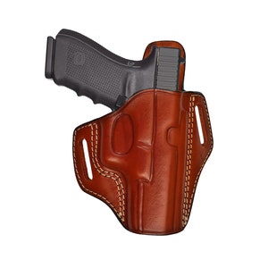 May include: A brown leather holster with a stitched design for a handgun. The holster has a belt loop and a cut-out for a magazine.