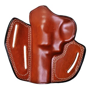 May include: A brown leather holster with stitching detail. The holster has a flap that covers the top of the gun and a belt loop on the back.