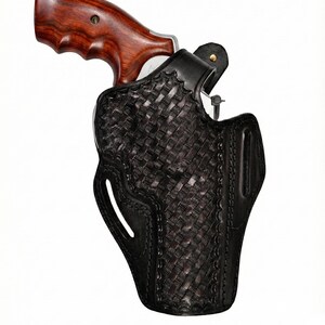 May include: A black leather holster with a woven pattern, holding a revolver. The revolver has a wooden grip. The holster features a belt loop and a decorative stitched edge.