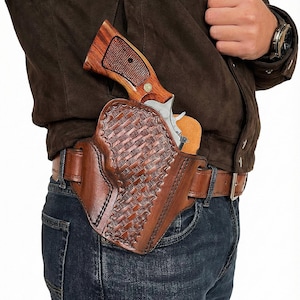 以下が含まれることがあります： 木製のグリップが付いた銀色のリボルバーを収納する、織り模様の茶色の革製ホルスター。 ホルスターは、青いジーンズを着用した茶色の革ベルトに取り付けられています。
