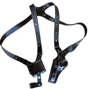 Peut inclure: Un holster d'&eacute;paule en cuir noir avec deux pochettes et des sangles r&eacute;glables. Le holster est con&ccedil;u pour &ecirc;tre port&eacute; sur la poitrine et le dos. Le cuir a une finition brillante et est fix&eacute; avec des rivets m&eacute;talliques.