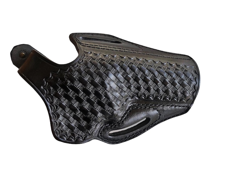 May include: A black leather holster with a basketweave pattern. The holster has a curved shape with a belt loop and a snap closure. The edges are stitched, and the leather appears to be thick and durable.