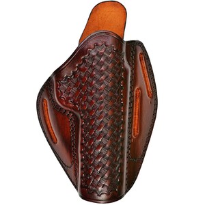 May include: A brown leather holster with a woven pattern. The holster has a flap on the top and a belt loop on the back.