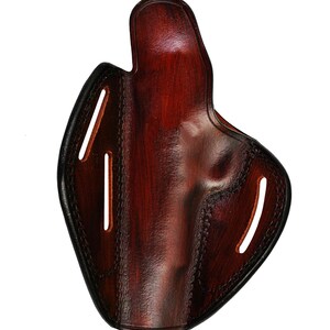 May include: A brown leather holster with stitching detail and cutouts for belt loops.
