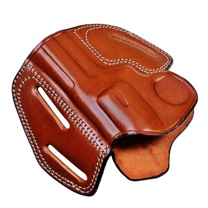 May include: A brown leather holster with white stitching. The holster has a cut-out for a gun and a belt loop.