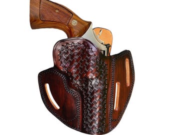 May include: A brown leather holster with a basketweave pattern and stitched edges, containing a revolver with a wooden grip. The holster features two vertical belt slots on the sides and a contoured shape designed to hold the firearm securely.