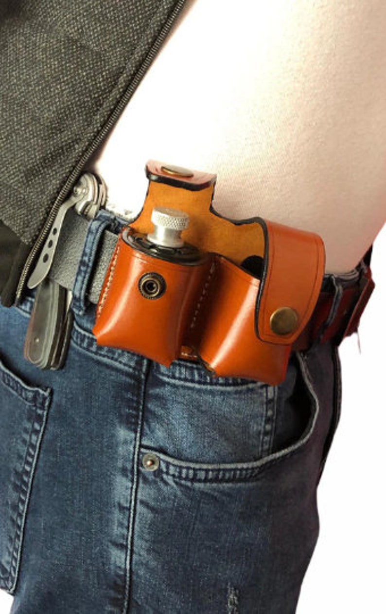 May include: A brown leather holster with two compartments for carrying small items. The holster is worn on a person's belt and has a silver metal snap closure.