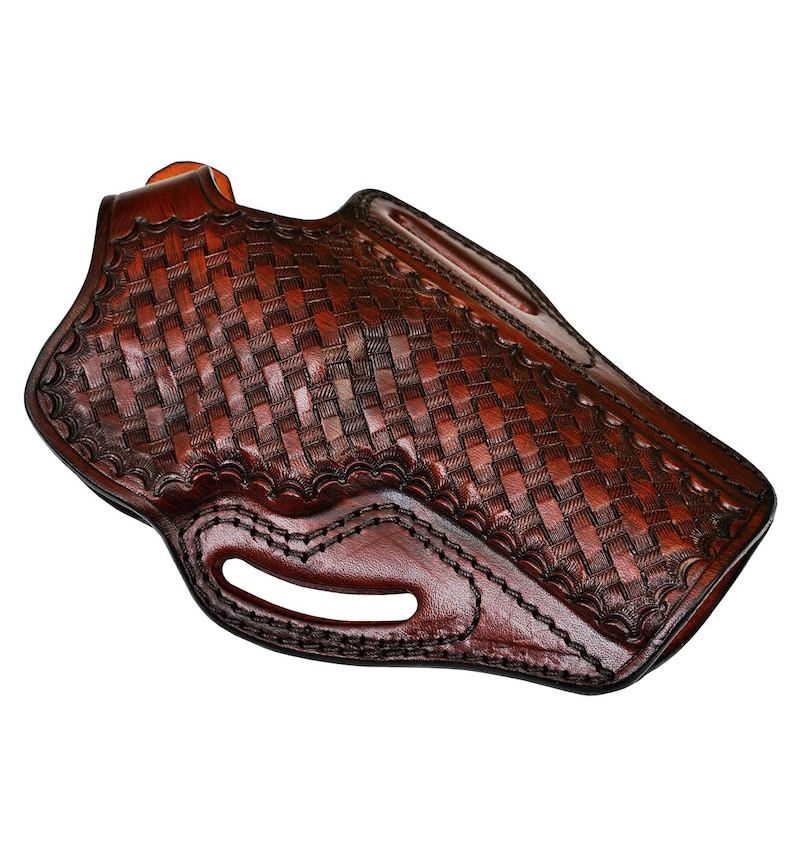 May include: A brown leather holster with a basketweave pattern. The holster has a curved shape with a belt loop and a cutout for the trigger guard. The leather is a rich, dark brown color with visible stitching.