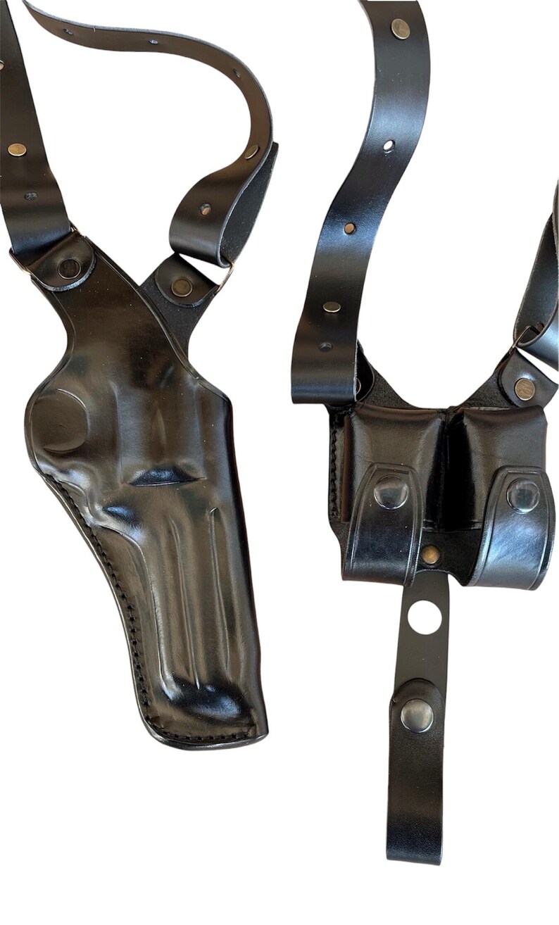 Pu&ograve; includere: Un porta-pistola a spalla in pelle nera con due tasche per caricatori. Il porta-pistola ha cinturini regolabili e una chiusura a scatto.