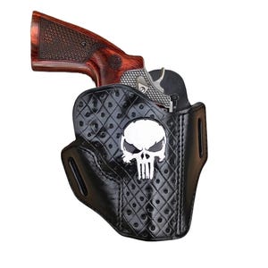 Może przedstawiać: Czarna skórzana kabura z diamentowym wzorem i białym motywem czaszki. W kaburze znajduje się srebrny rewolwer z drewnianym uchwytem.