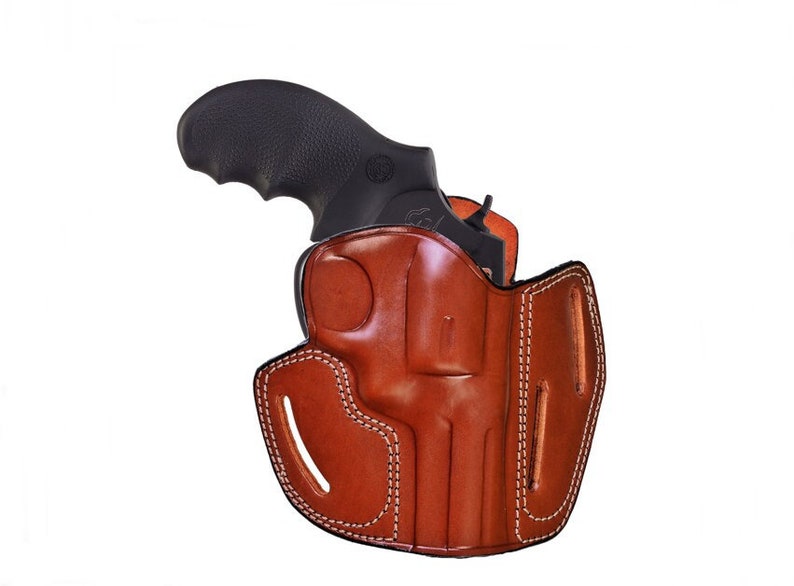 May include: A brown leather holster with a stitched design for a revolver. The holster is designed to be worn on the belt.