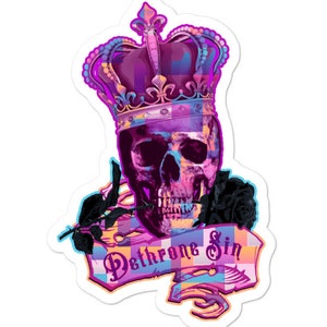 Könnte beinhalten: Ein bunter Schädel, der eine lila und rosafarbene Krone mit einer schwarzen Rose trägt. Der Schädel ist von einem Banner mit dem Text "Dethrone Sin" in Rosa und Blau umgeben.