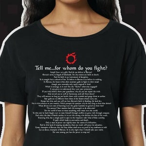 Puede incluir: Camiseta negra con un estampado blanco de un símbolo rojo y el texto "Tell me...for whom do you fight?" El texto es una cita del videojuego "Dark Souls".