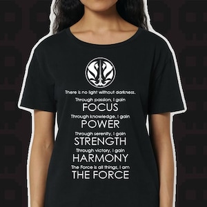 May include: Black t-shirt with a white symbol and text that reads: "There is no light without darkness. Through passion, I gain FOCUS. Through knowledge, I gain POWER. Through serenity, I gain STRENGTH. Through victory, I gain HARMONY. The Force is all things, I am THE FORCE."