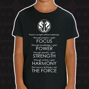 May include: Black t-shirt with a white symbol and text that reads: "There is no light without darkness. Through passion, I gain FOCUS. Through knowledge, I gain POWER. Through serenity, I gain STRENGTH. Through victory, I gain HARMONY. The Force is all things, I am THE FORCE."