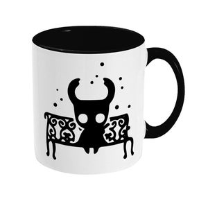 Può includere: Tazza in ceramica bianca con interno e manico neri, con una grafica di un personaggio di cartoni animati nero seduto su una panchina. Il design include piccoli punti neri attorno al personaggio. Una tazza da caffè unica ed elegante.