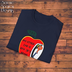 May include: A navy blue t-shirt with a red apple graphic. The apple has a white car inside with the text "My other car is RFK Jr's brain".