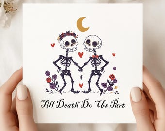 Può includere: Biglietto quadrato con un'illustrazione di due scheletri che si tengono per mano, circondati da cuori e decorazioni floreali. Gli scheletri sono adornati con una corona floreale e un papillon. Il testo "Till Death Do Us Part" è in basso.