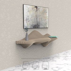 Op de afbeelding: Een houten wandplank met een golvend, organisch ontwerp. De plank is gemaakt van meerdere lagen hout, waardoor een 3D-effect ontstaat. De plank is gemonteerd aan een witte muur en heeft een vaas met blauwe bloemen en een boek erop.