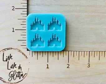 May include: A blue silicone mold with four castle-shaped cavities. The mold is approximately 1 inch by 1 inch.