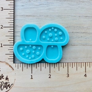 May include: A blue silicone mold for making mushroom-shaped resin crafts. The mold has four sections, including a mushroom cap with a dotted texture, a mushroom cap with a smooth texture, a mushroom stem, and a small circle.