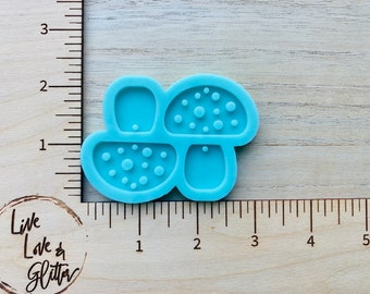 May include: A blue silicone mold for making mushroom-shaped resin crafts. The mold has four sections, including a mushroom cap with a dotted texture, a mushroom cap with a smooth texture, a mushroom stem, and a small circle.