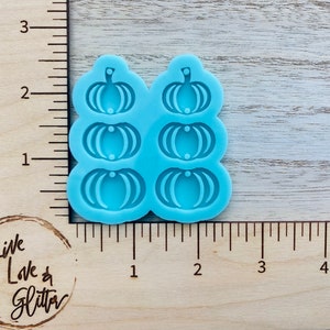 May include: A blue silicone mold with six pumpkin shapes. The mold is designed for making small pumpkin-shaped decorations.