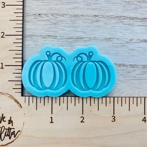 May include: A blue silicone mold with two pumpkin shapes. The mold is about 1 inch wide and 1 inch tall.