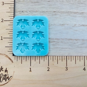 May include: A blue silicone mold with six leaf-shaped cavities. Each cavity has a small hole at the top.