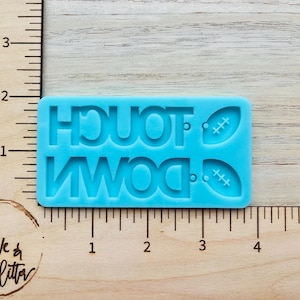 May include: Blue silicone mold with the words "TOUCHDOWN" and two footballs.