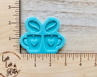 May include: A light blue silicone mold for making earrings. The mold features two coffee cups with hearts and two coffee beans.