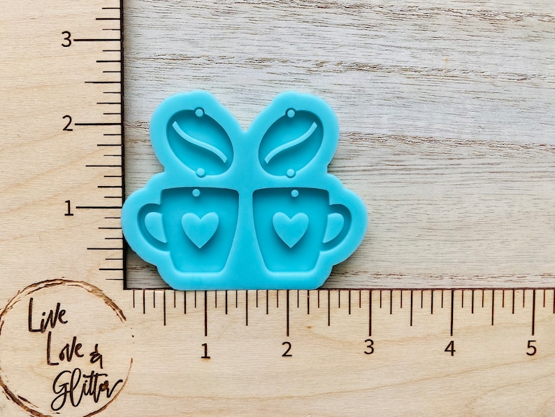 May include: A light blue silicone mold for making earrings. The mold features two coffee cups with hearts and two coffee beans.