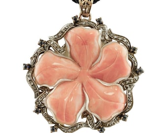 May include: A pink carved flower pendant with a silver and diamond filigree frame and black sapphire accents. The pendant is on a black cord.