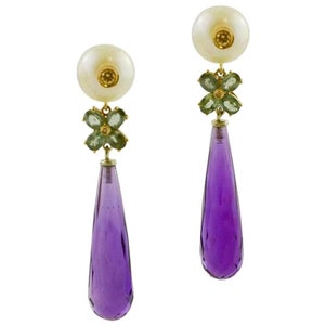 May include: A pair of dangle earrings with a pearlescent white top, a green gemstone flower, and a teardrop-shaped amethyst stone.