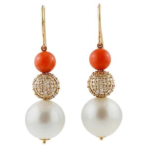 May include: A pair of gold-tone drop earrings. Each earring features a vibrant orange bead, a pave-set crystal bead, and a large white pearl. The earrings have a classic, elegant design.