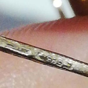 May include: A close-up of a silver-colored metal bar with a textured surface.