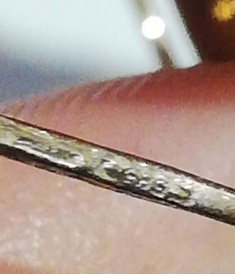 May include: A close-up of a silver-colored metal bar with a textured surface.