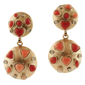 May include: A pair of gold earrings with a dangling design. Each earring features two round, textured gold discs with a cluster of red coral hearts and small diamonds.