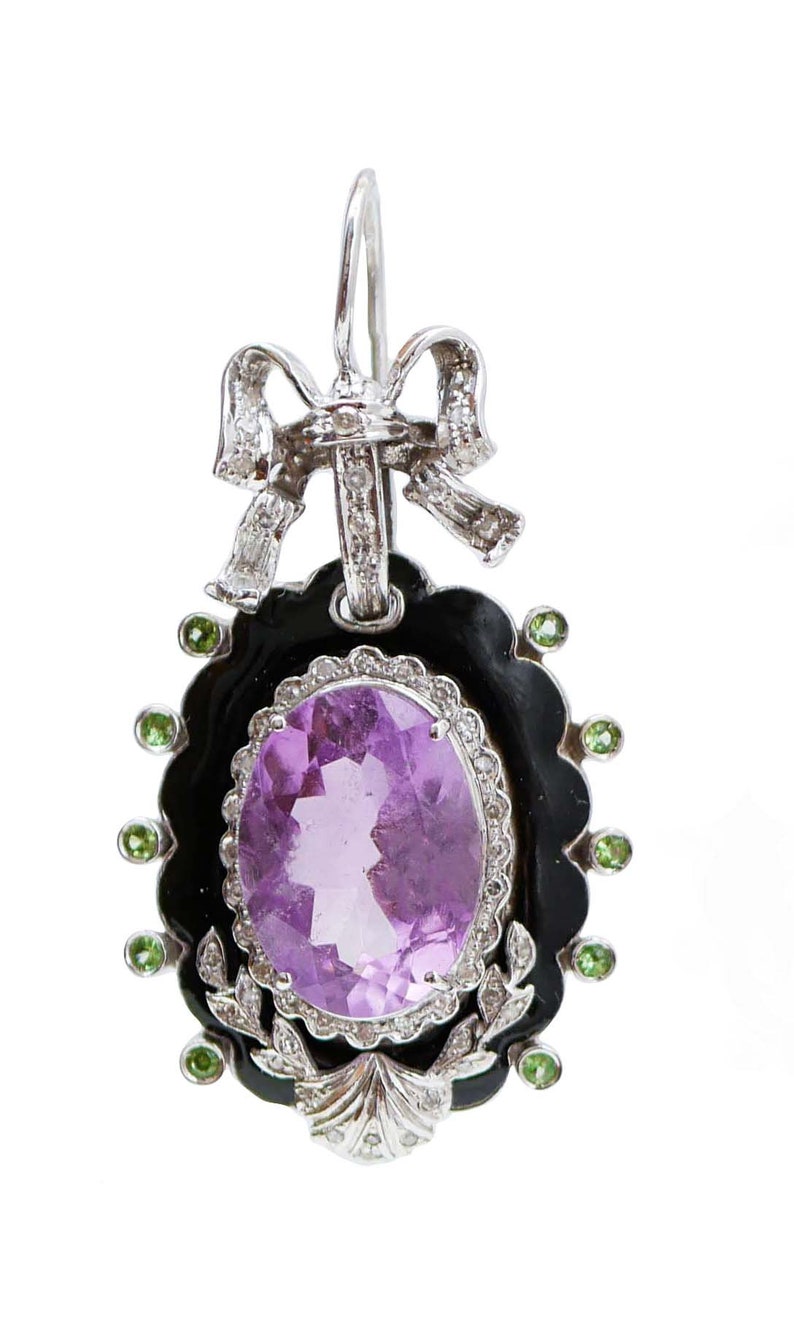 May include: An ornate earring featuring a large oval amethyst gemstone set in a black frame, surrounded by green accents. The earring has a silver bow at the top and a decorative leaf design at the bottom. The earring is designed for pierced ears.