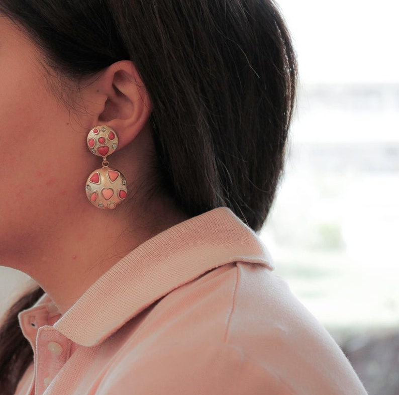 May include: A pair of gold tone dangle earrings with pink and white heart-shaped stones.