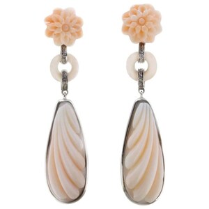 May include: A pair of dangle earrings with a carved shell design and a flower charm. The earrings are made of white metal and have a pink shell color.
