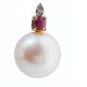 May include: A single pearl earring with a gold setting. The earring features a large, round, white pearl. Above the pearl is a square gold setting with a red gemstone, topped with a small diamond accent. The background is white.
