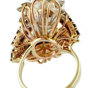 May include: A gold ring featuring a large pearl set within a diamond and sapphire halo. The ring is crafted in a three-tone gold setting.