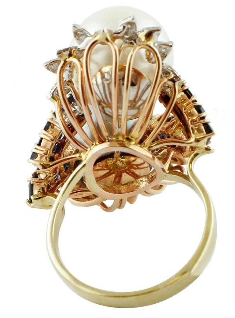 May include: A gold ring featuring a large pearl set within a diamond and sapphire halo. The ring is crafted in a three-tone gold setting.