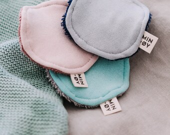 May include: Three reusable makeup remover pads in pink, light blue, and teal. Each pad has a white label with the text "MIN.OY" printed on it.