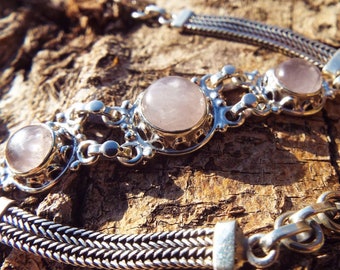 Puede incluir: Una pulsera de plata con tres piedras de cuarzo rosa. La pulsera tiene un diseño de cadena delicado y un cierre de broche.