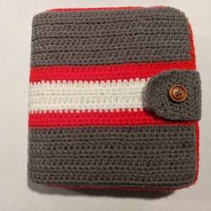 May include: Gray crocheted pouch with a red and white striped band and a gray crocheted flap with a wooden button.