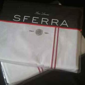 May include: Two white sheets with red and white stripes, packaged together. The packaging has the text "Fine Linens SFERRA" printed on it.