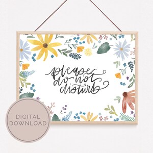 May include: A framed floral print with the words "please do not disturb" in elegant script. The artwork features a watercolor design with yellow, blue, and orange flowers, and green leaves. A digital download is available.